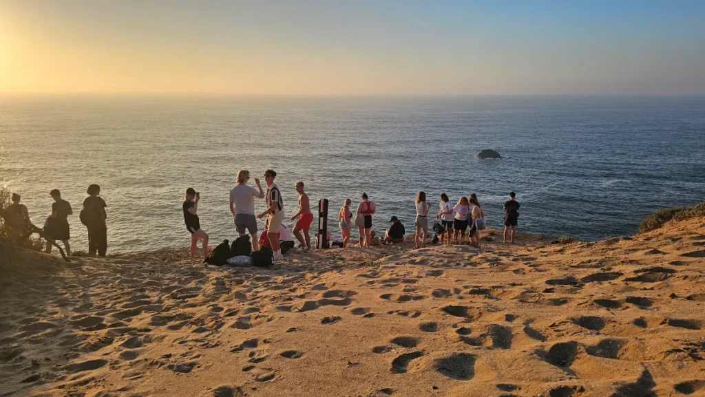 Strender i Taghazout i solnedgang: en gruppe surfere på sanden