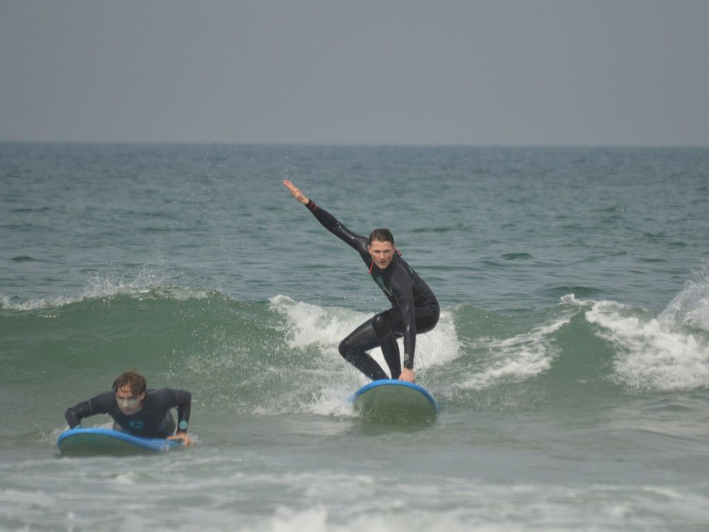 Surfista principiante de pie sobre una tabla de espuma en Tamraght, Marruecos