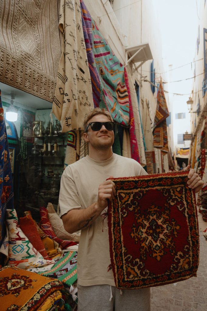 Traveller holding a Moroccan rug in a carpet shop in the Essaouira medina