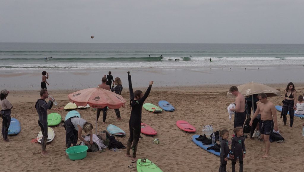 Surfferie med familien i Marokko: forældre og børn med surfboards på stranden