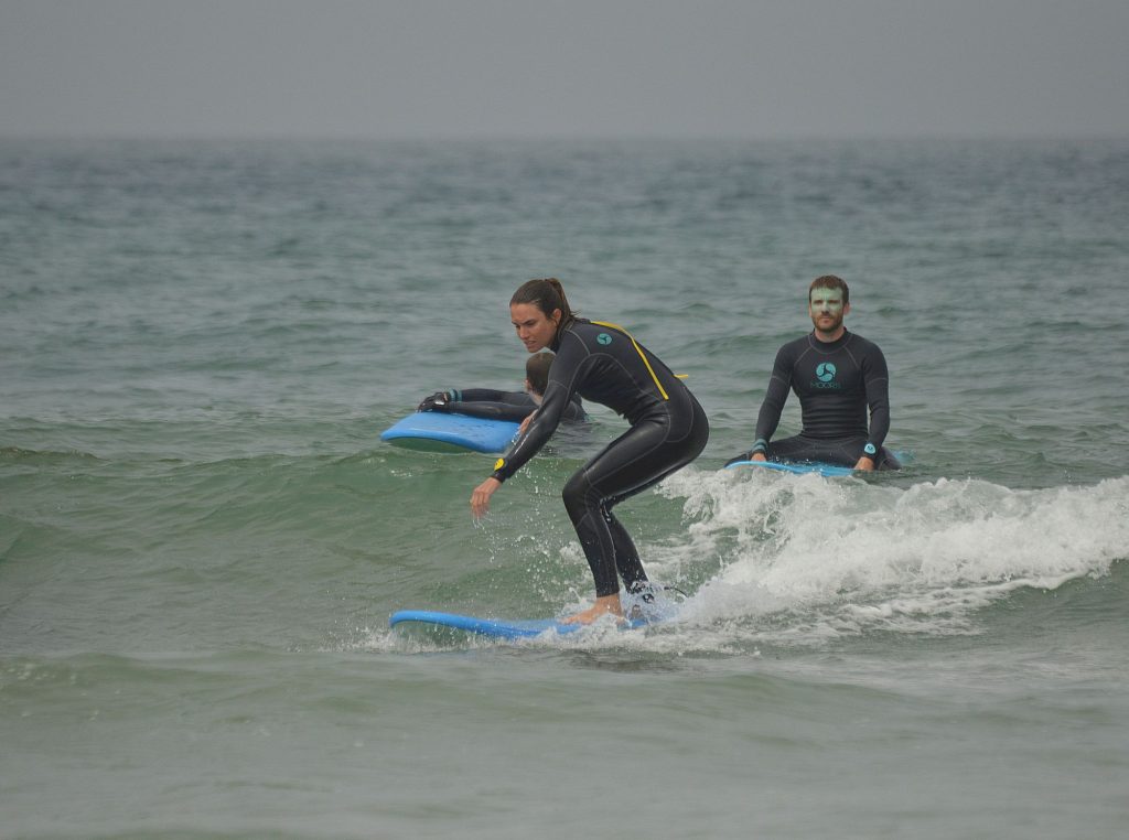 Dos alumnos de surf en la misma ola de espuma durante una clase en Tamraght