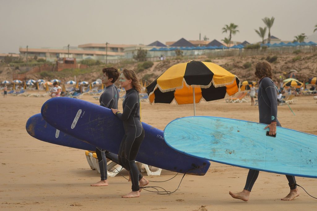 Surfing in Morocco: surfers carrying their boards to the waves near Taghazout