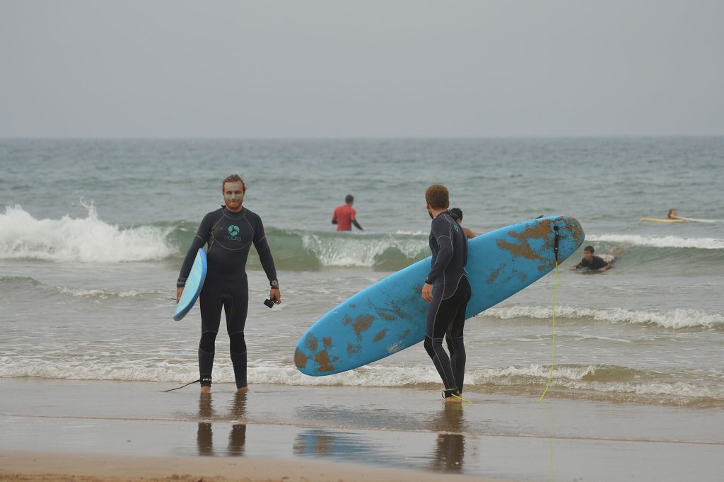 Two surfers walking into the ocean with their boards in Tamraght