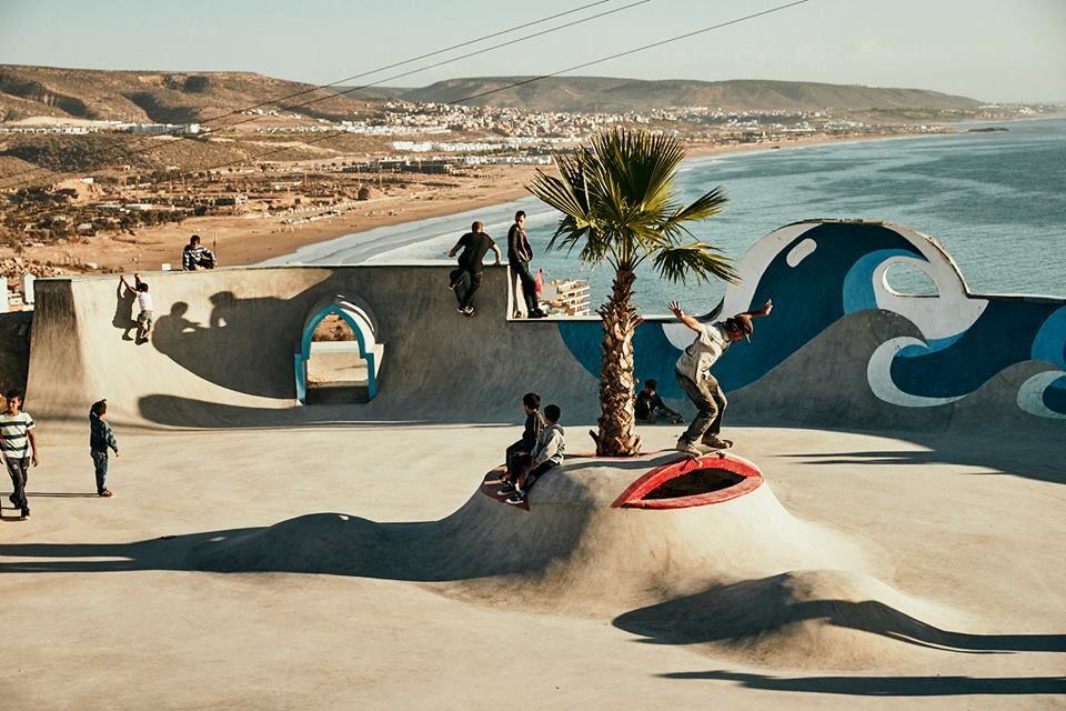 Skateåkare i bowlen i skateparken i Taghazout med Atlanten och Taghazout Bay i bakgrunden