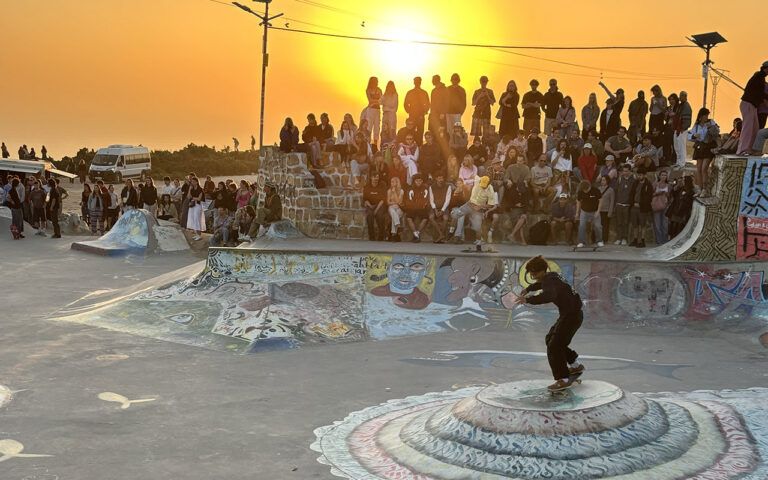 Publik tittar på en skateåkare i solnedgången i skateparken i Taghazout, Marocko