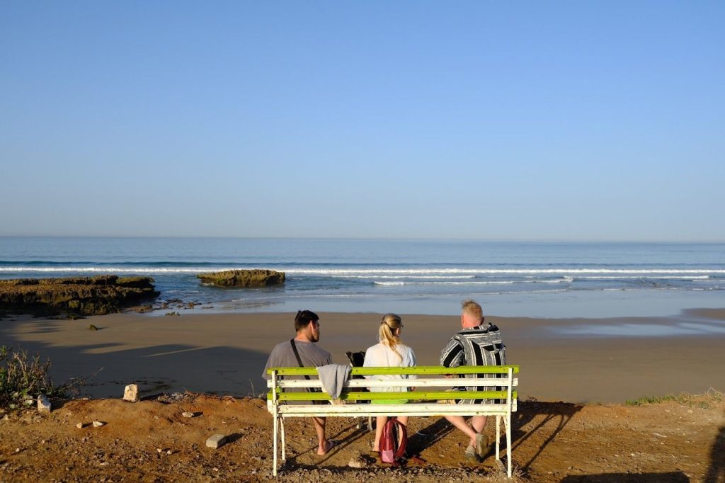 Tre personer på en benk med utsikt over stranden i Tamraght og havet
