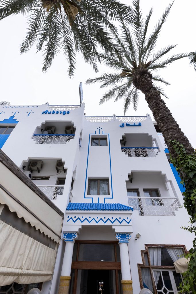 Front of the Twist Surf camp house with its white and blue facade and palm tree, Taghazout Bay